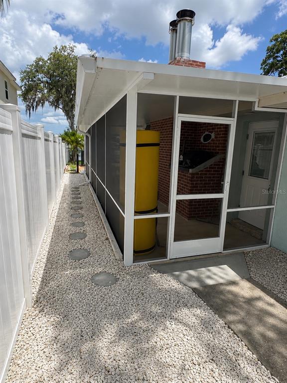 A screened-in porch features a yellow water heater, brick wall, and a white door — 5431 FOLEY SQUARE, NEW PORT RICHEY, FL