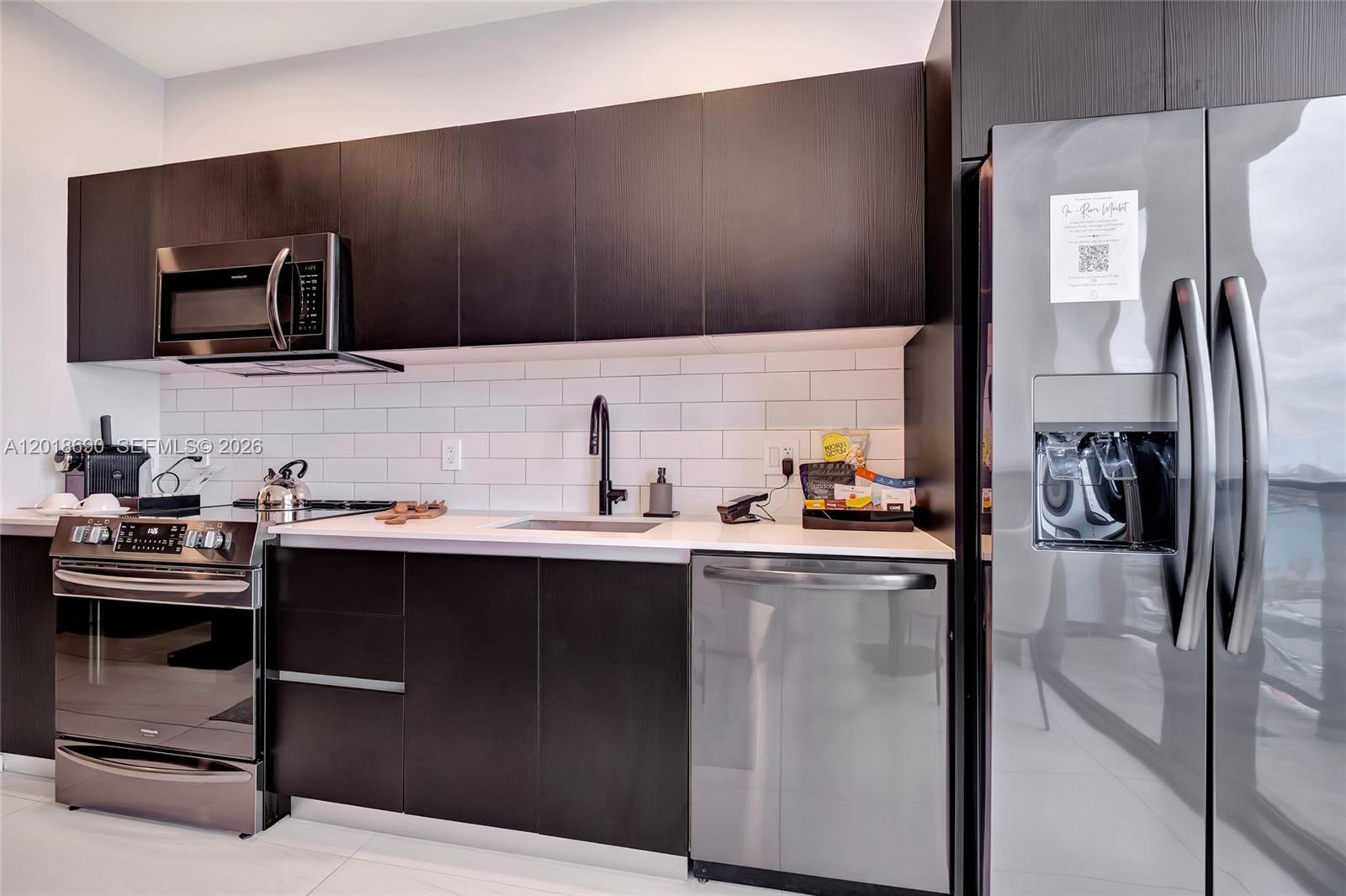 A modern kitchen features dark wood cabinetry, stainless steel appliances, and white subway tile backsplashes — 398 NE 5th St # 1407, Miami FL 33132, MIAMI, FL