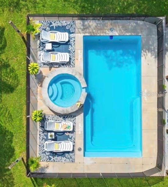 An aerial view shows a rectangular swimming pool and a circular spa inside a fenced enclosure — 313 CRYSTAL BEACH AVENUE, CRYSTAL BEACH, FL