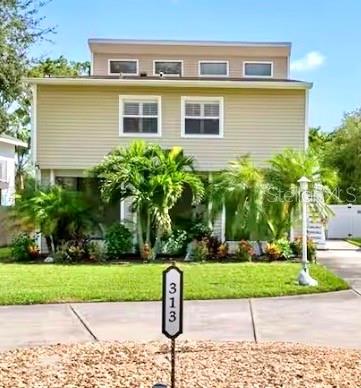 A two-story house with light-colored siding, a front lawn, and a house number sign — 313 CRYSTAL BEACH AVENUE, CRYSTAL BEACH, FL