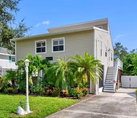 A two-story house with beige siding, palm trees, and an exterior staircase leading to a deck — 313 CRYSTAL BEACH AVENUE, CRYSTAL BEACH, FL