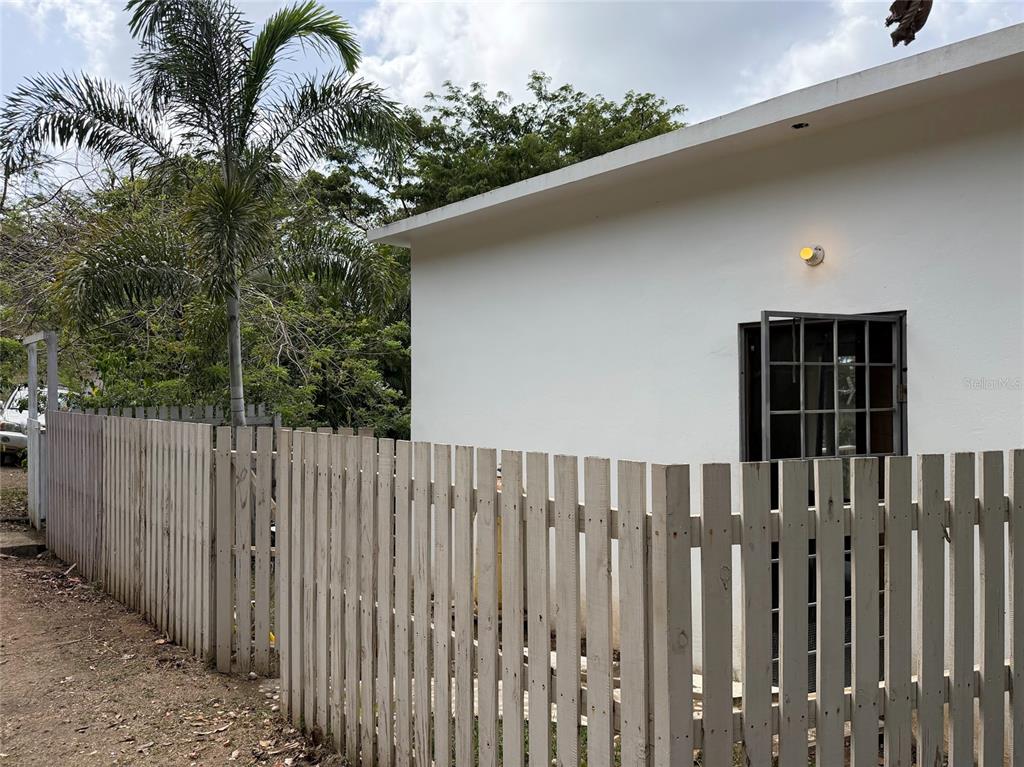 A white exterior wall of a building sits behind a wooden picket fence — 311 VILLA BORINQUEN, VIEQUES, PR