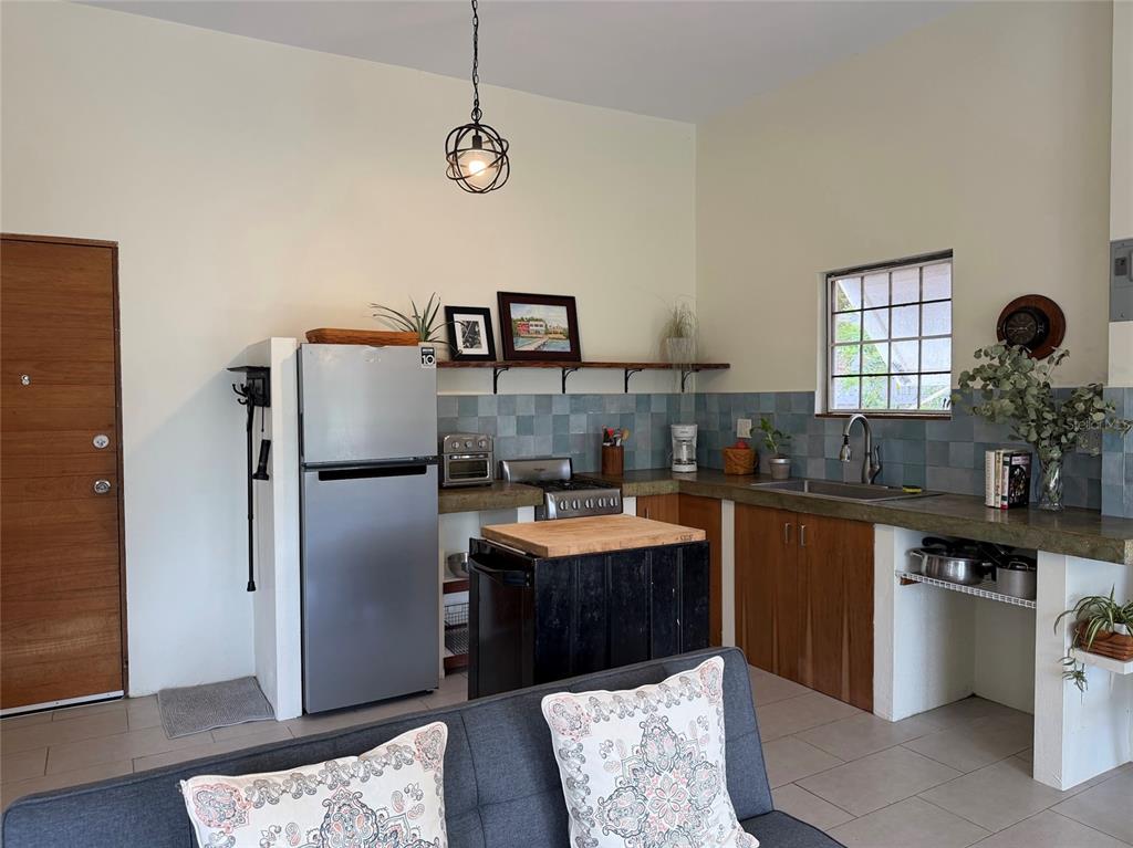 A kitchen features a stainless steel refrigerator, concrete countertops, blue tile backsplash, and a wooden island — 311 VILLA BORINQUEN, VIEQUES, PR