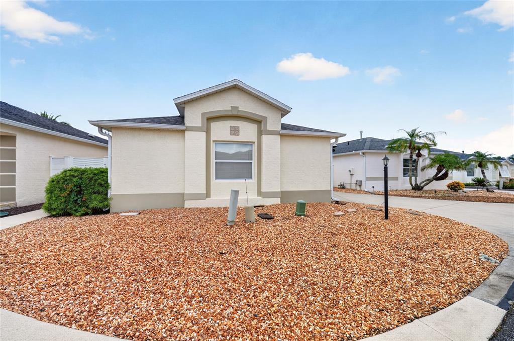 A single-story house with a beige stucco exterior and a gravel front yard — 1049 JACKSON STREET, THE VILLAGES, FL