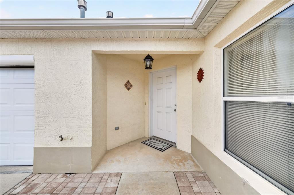 The exterior entrance features a white front door, a garage, and a paved walkway — 1049 JACKSON STREET, THE VILLAGES, FL