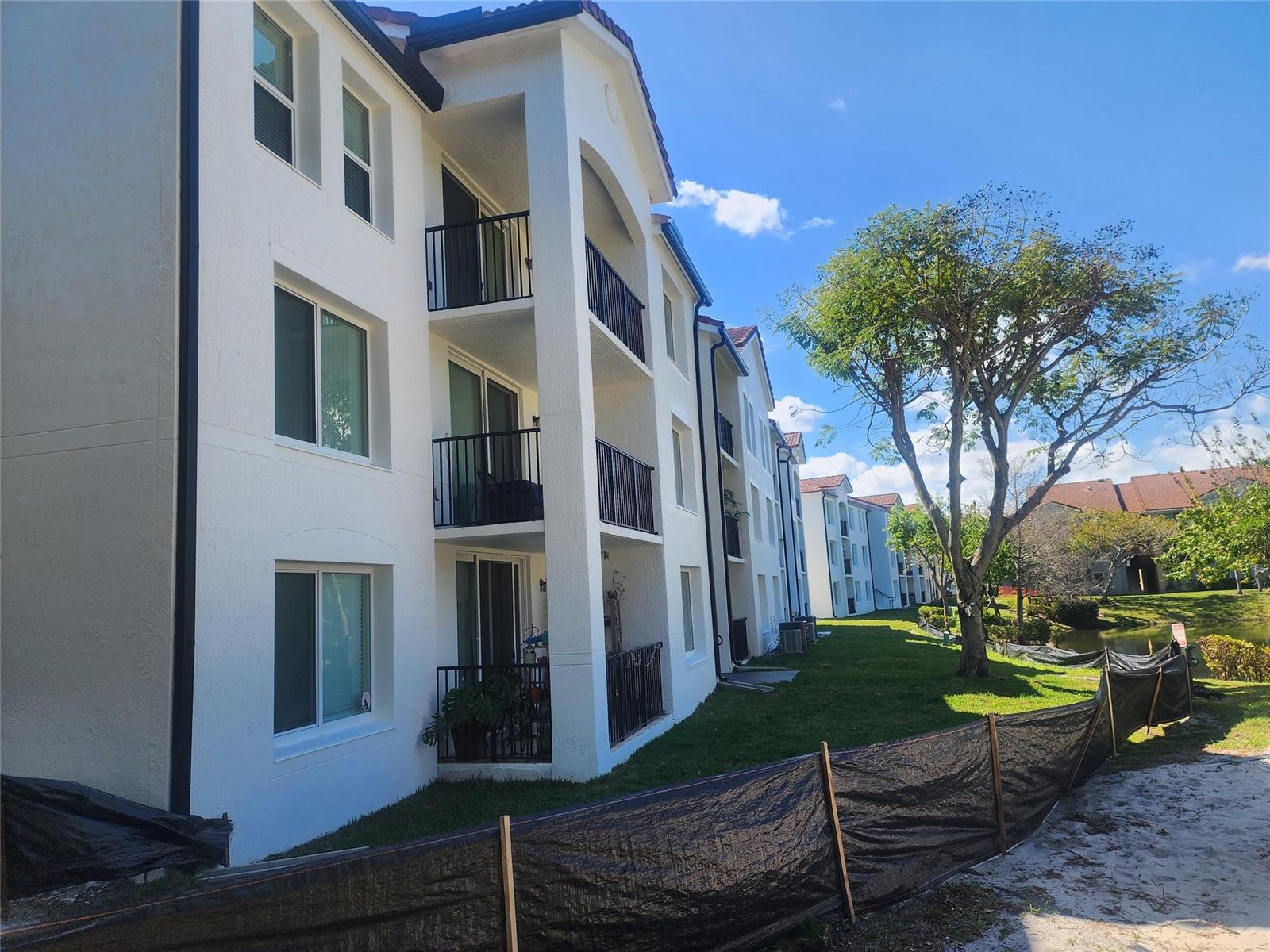 A paved driveway leads to a multi-story apartment building surrounded by palm trees and fountains — 317 Villa Circle # 317, Boynton Beach FL 33435, BOYNTON BEACH, FL