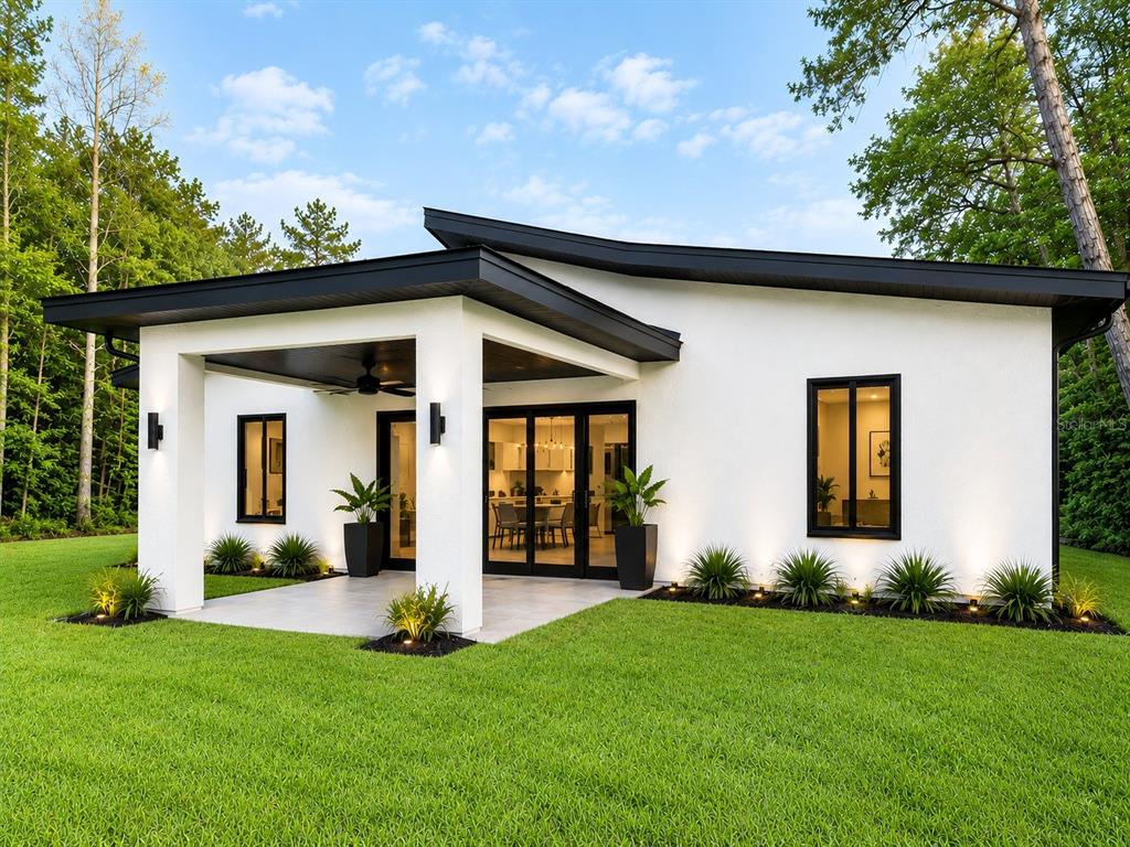A modern white house with a black roof and trim features a covered patio area — 8252 SW 129TH STREET, OCALA, FL
