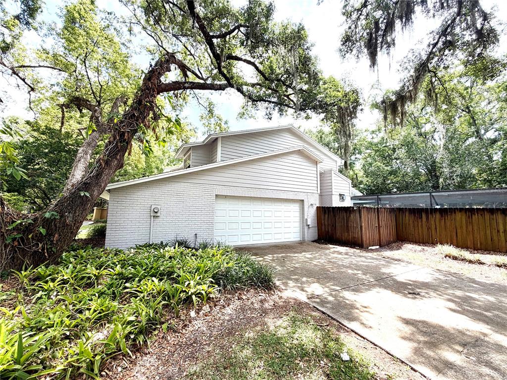 A two-story house with a white brick garage, a concrete driveway, and large oak trees — 14904 LAKE FOREST DRIVE, LUTZ, FL