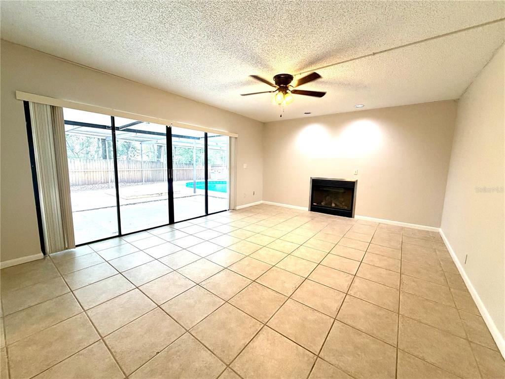 A living room features tile flooring, a fireplace, a ceiling fan, and sliding glass doors — 14904 LAKE FOREST DRIVE, LUTZ, FL