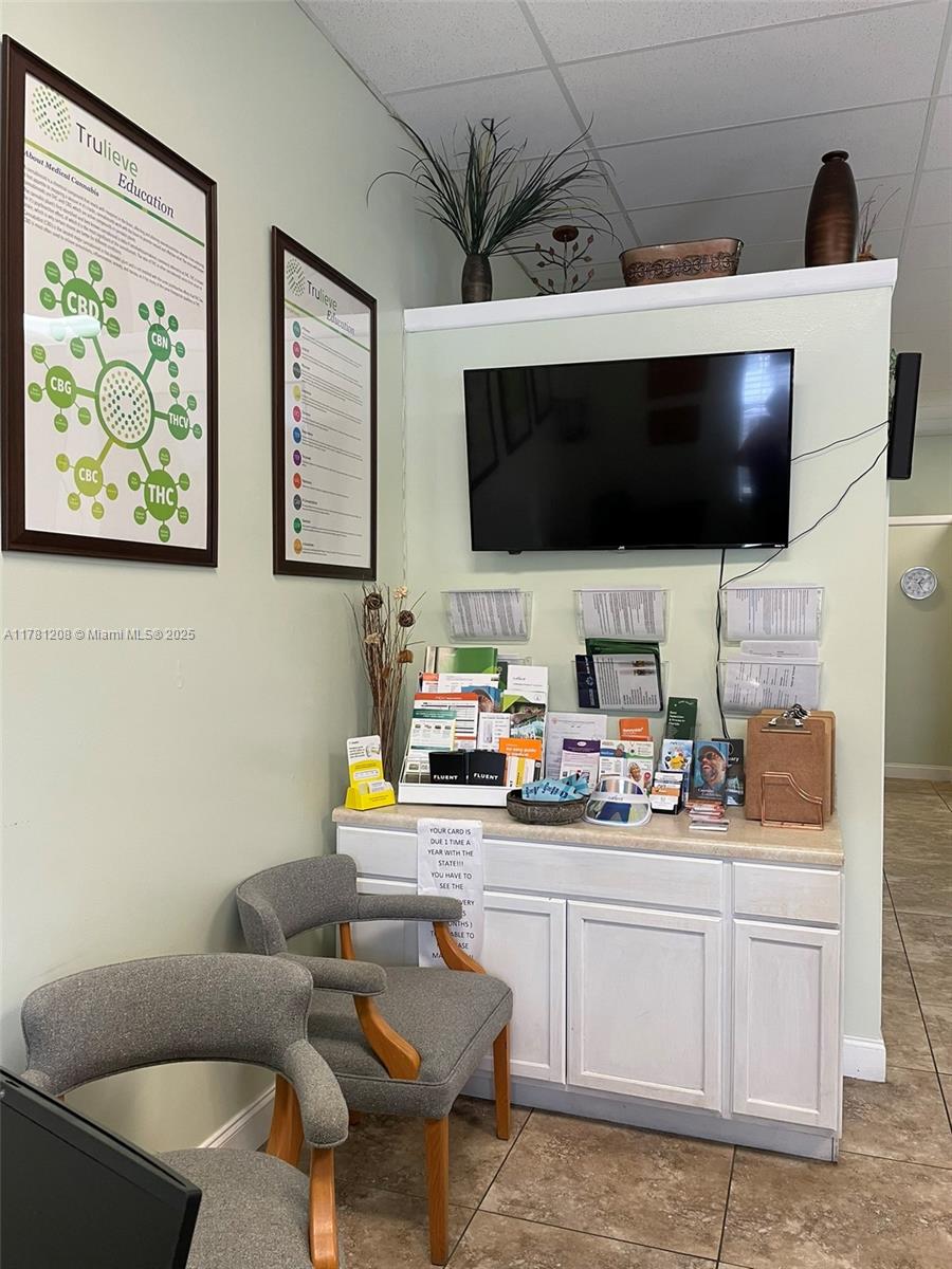 A waiting area features two gray chairs, a white cabinet, and educational posters on walls — PORT ST. LUCIE, FL