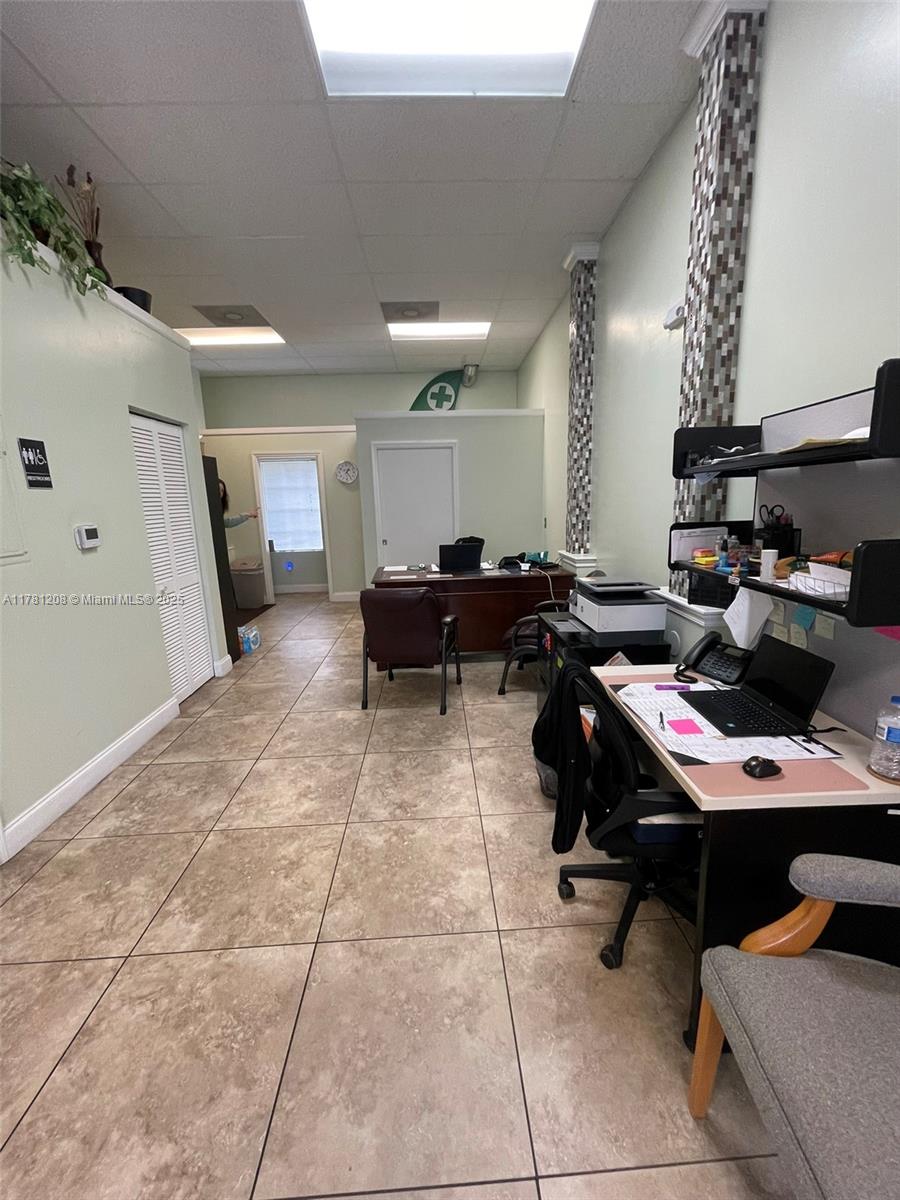 An office space features tile flooring, a drop ceiling, and two desks with computers — PORT ST. LUCIE, FL