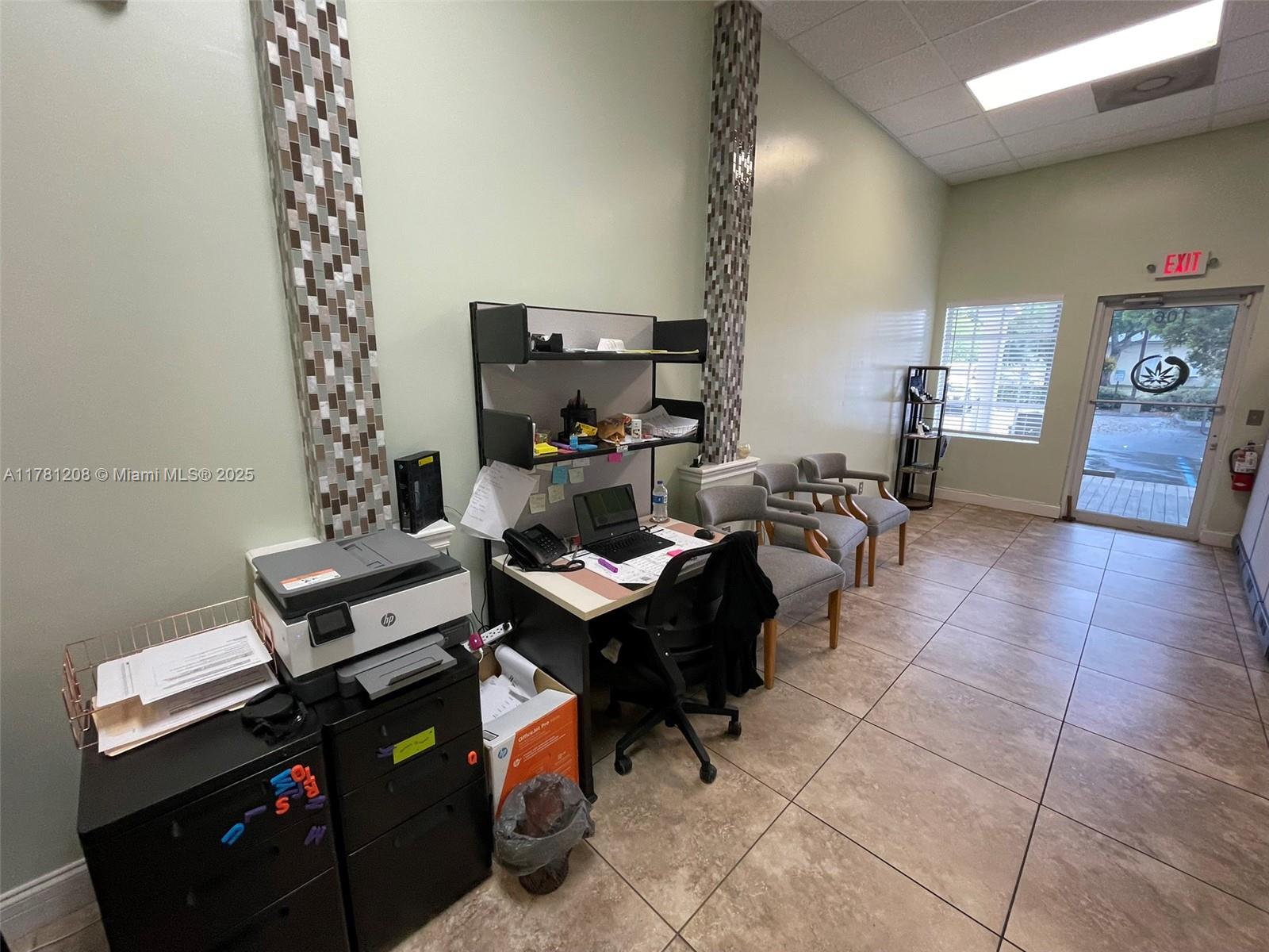 A small office space features a desk, printer, chairs, and tiled floors — PORT ST. LUCIE, FL