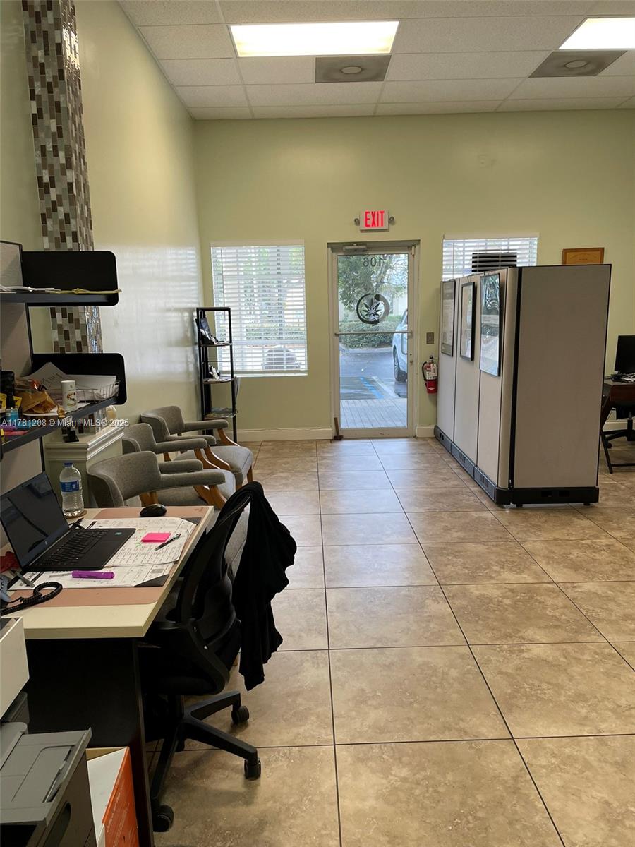 An office interior features a desk, waiting chairs, cubicle partitions, and a glass entry door — PORT ST. LUCIE, FL
