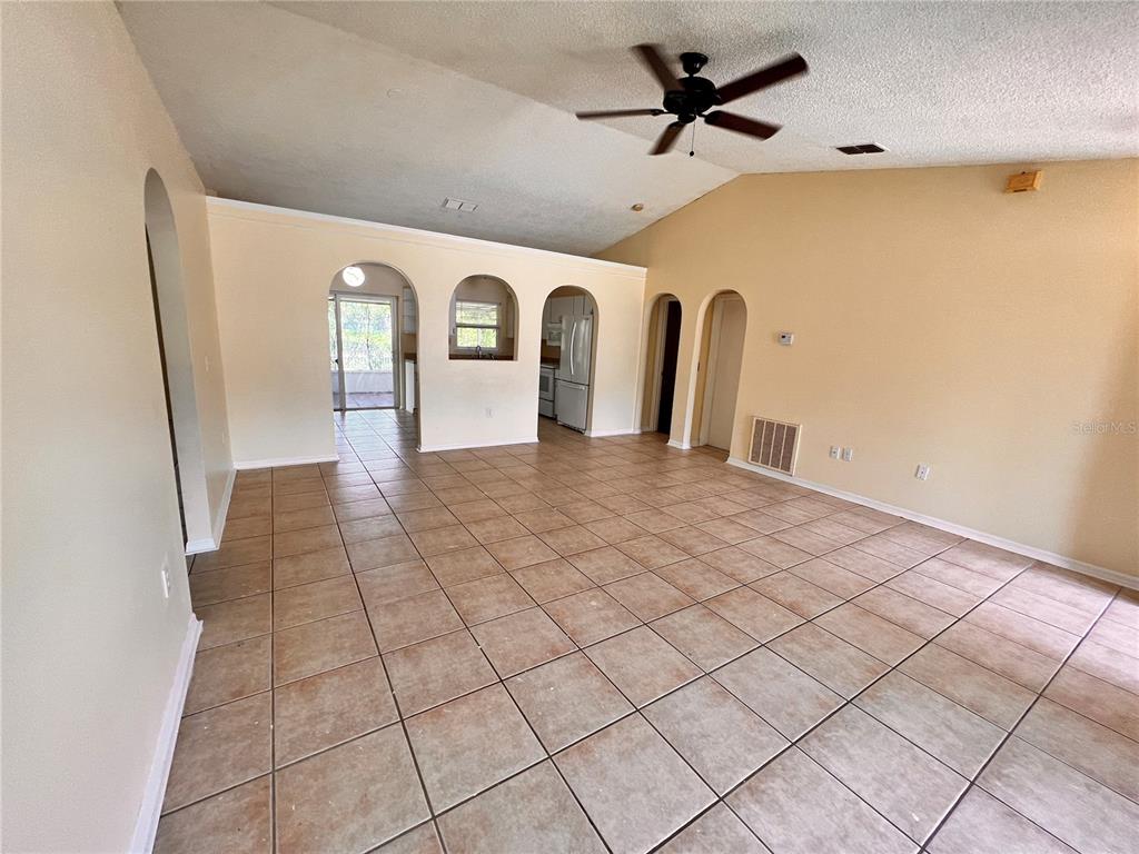An open living area features tan tile flooring, vaulted ceilings, and several arched doorways — 390 FORT SMITH BOULEVARD, DELTONA, FL