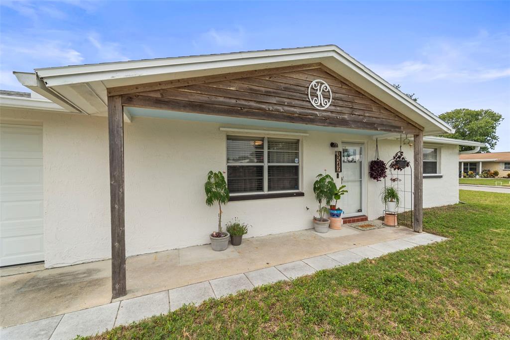 The exterior of a single-story house features a covered front porch with a wooden gable — 3547 WILSON DRIVE, HOLIDAY, FL