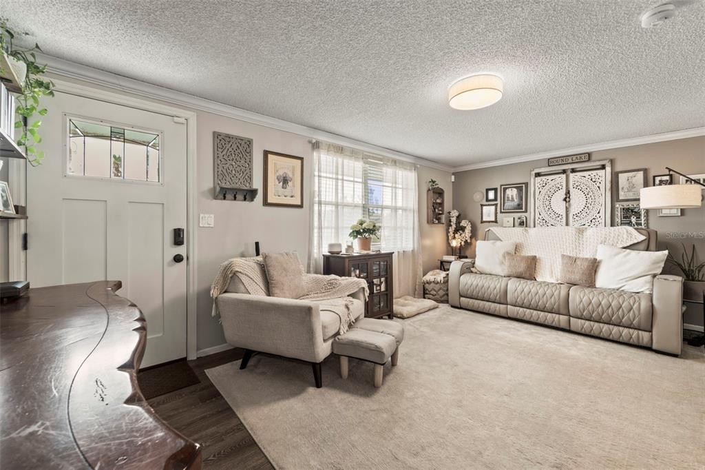 A living room features a light-colored sofa, an armchair with an ottoman, and neutral decor — 3547 WILSON DRIVE, HOLIDAY, FL