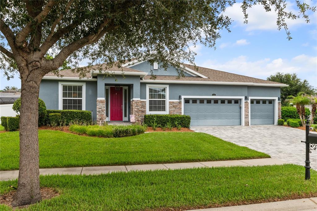 A single-story house with a blue exterior, stone accents, a red front door, and a driveway — 433 AMETHYST AVENUE, AUBURNDALE, FL
