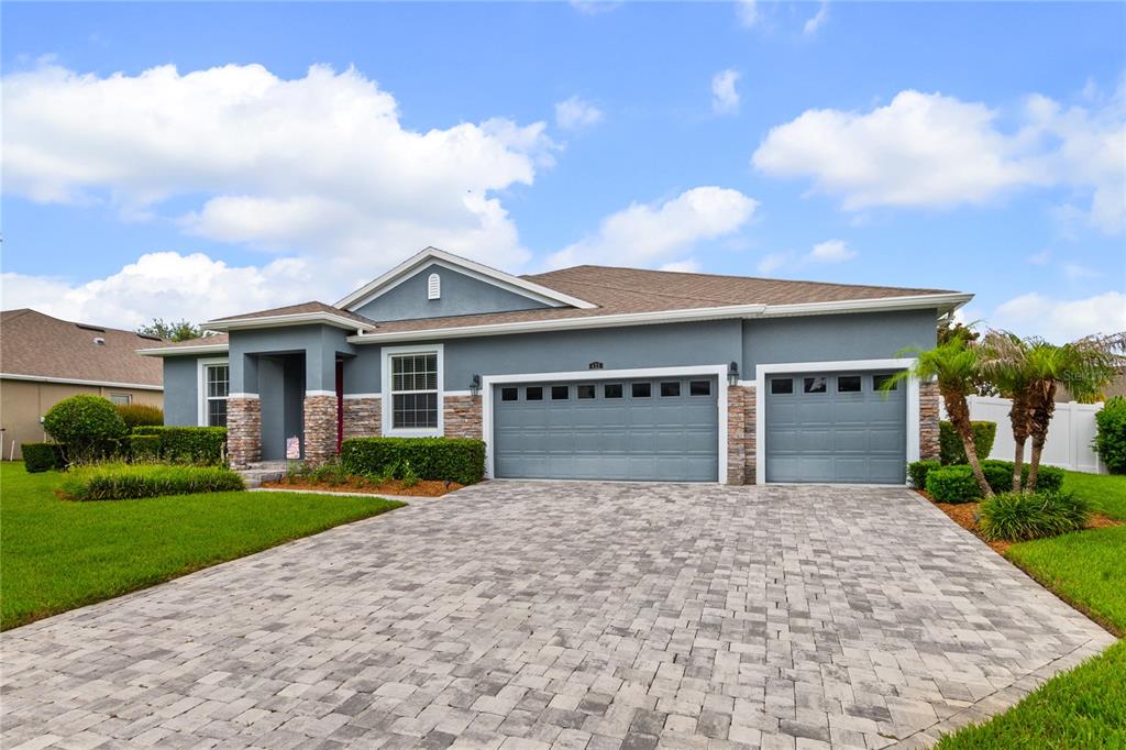 A single-story house with a gray stucco exterior, stone accents, and a paved driveway — 433 AMETHYST AVENUE, AUBURNDALE, FL