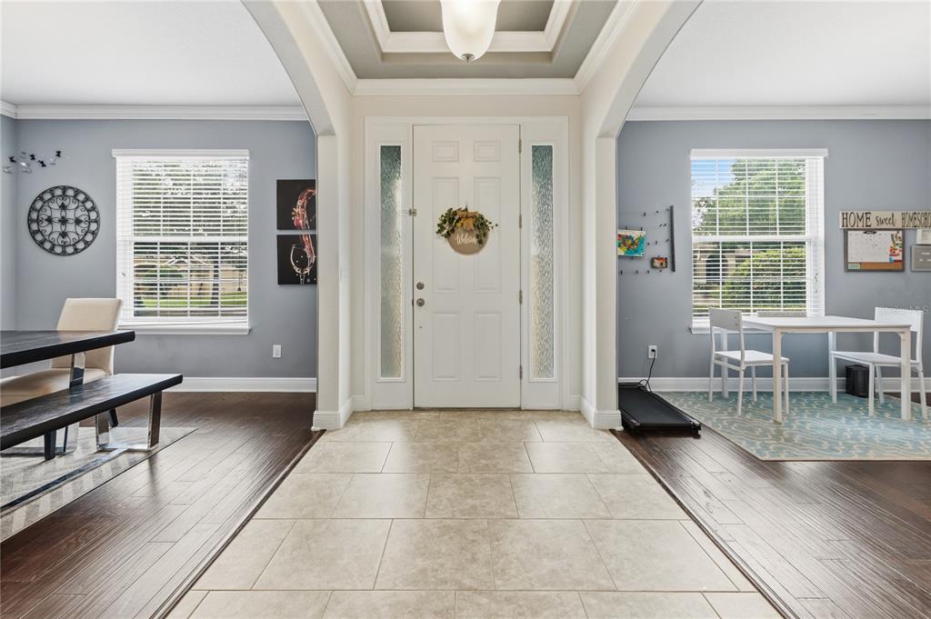 A tiled entryway leads to a white front door flanked by two rooms with hardwood floors — 433 AMETHYST AVENUE, AUBURNDALE, FL