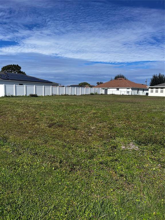 A vacant grassy lot is bordered by a white fence and nearby residential houses — 725 LEONARDO COURT, KISSIMMEE, FL