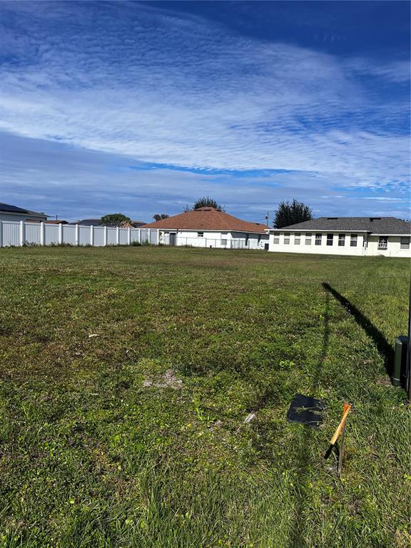 A vacant grassy lot sits in front of a white fence and two residential houses — 725 LEONARDO COURT, KISSIMMEE, FL