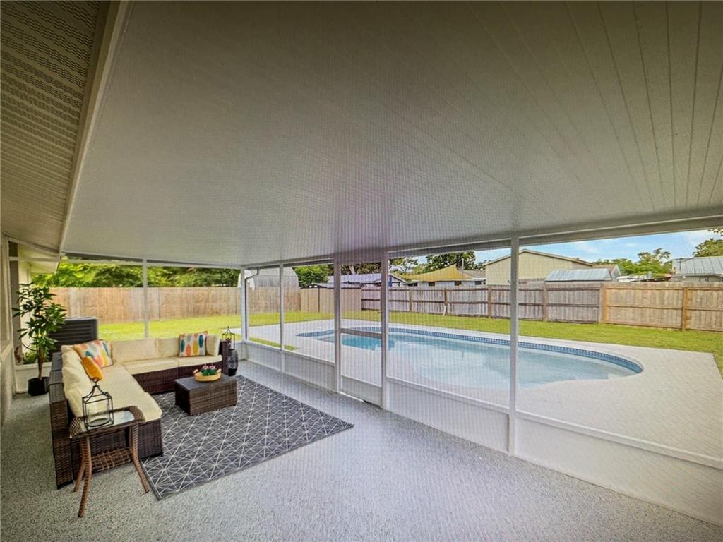 A covered screened-in patio features a seating area overlooking a backyard swimming pool — 3032 GOLDEN RAIN DRIVE, SARASOTA, FL