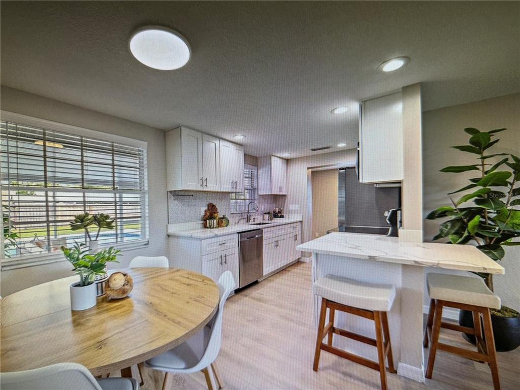 A kitchen with white cabinets, marble-look countertops, a breakfast bar, and an adjacent dining area — 3032 GOLDEN RAIN DRIVE, SARASOTA, FL