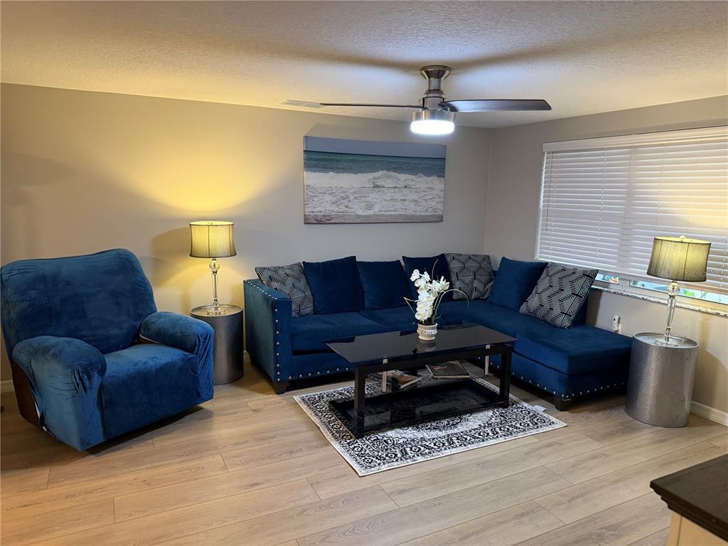 A living room features a blue sectional sofa, a matching armchair, and a coffee table — 3032 GOLDEN RAIN DRIVE, SARASOTA, FL