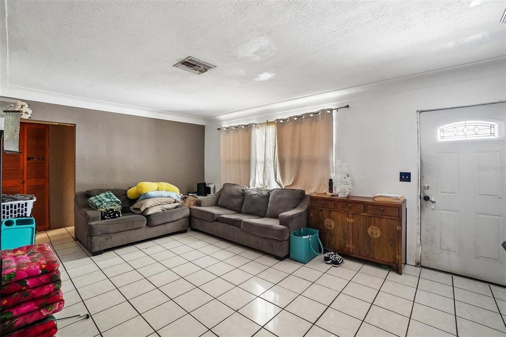 A living room features white tile floors, two gray sofas, and a wooden cabinet — 3211 30TH STREET N, ST PETERSBURG, FL