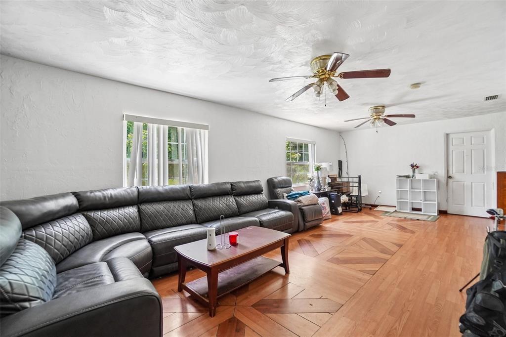 A living room features a large dark leather sectional, wood flooring, and two ceiling fans — 3211 30TH STREET N, ST PETERSBURG, FL