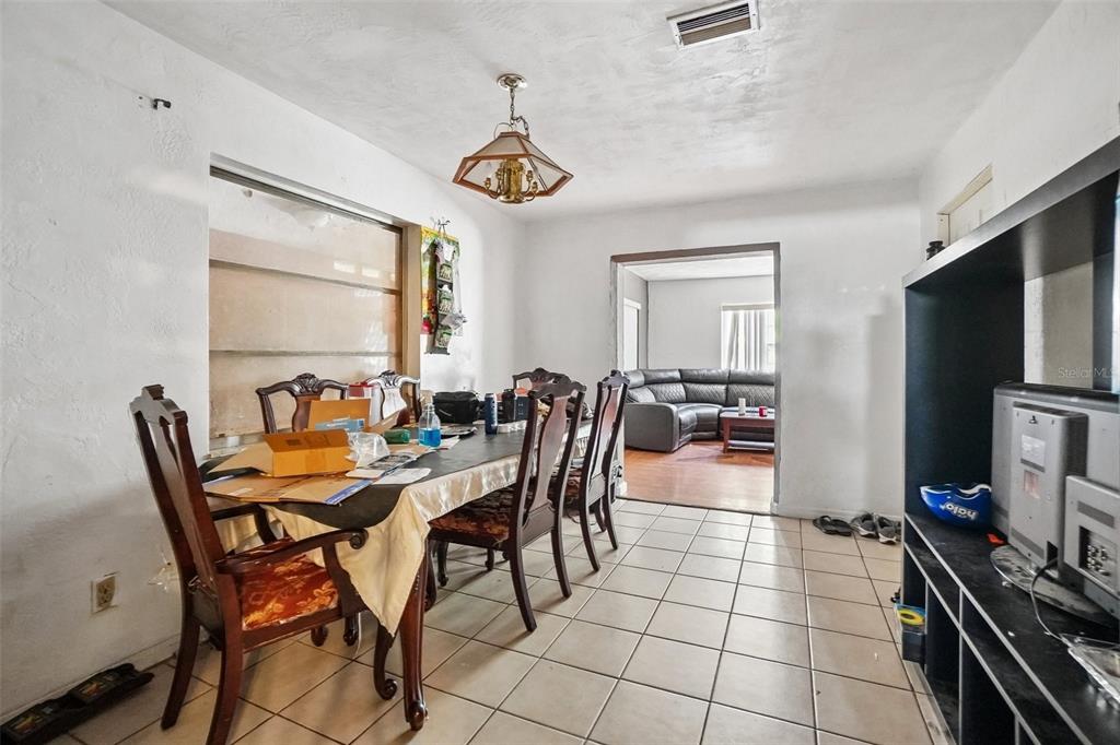 A dining room with tile floors and a wooden table leads into a living area — 3211 30TH STREET N, ST PETERSBURG, FL