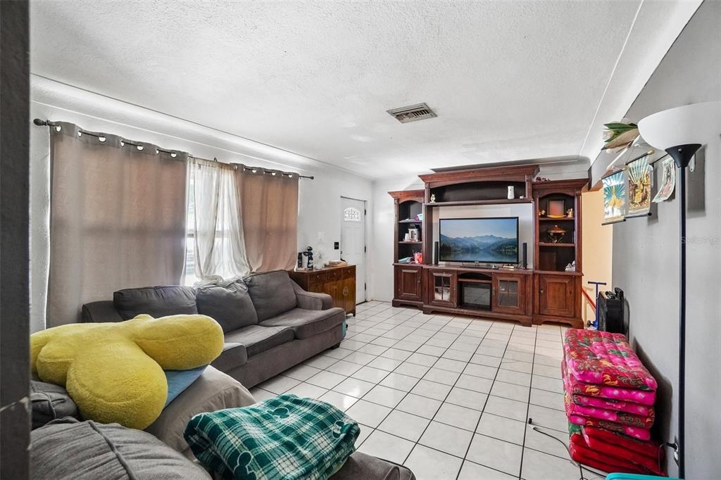 A living room features white tile floors, a large wooden entertainment center, and gray sofas — 3211 30TH STREET N, ST PETERSBURG, FL