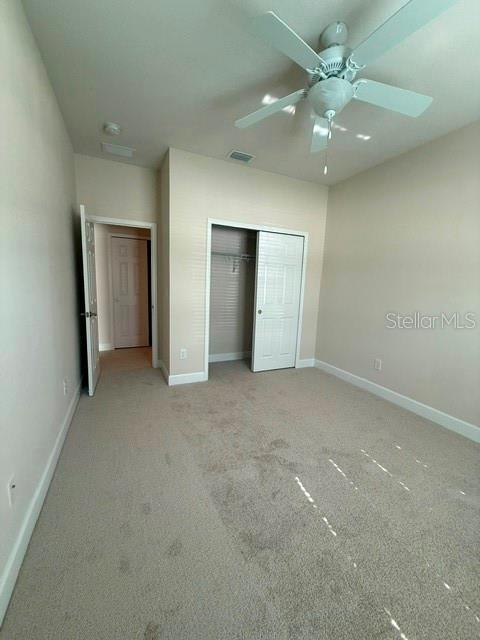 A bedroom with beige carpet, a ceiling fan, and a closet with white sliding doors — 2834 SHETLAND RIDGE DRIVE, VALRICO, FL