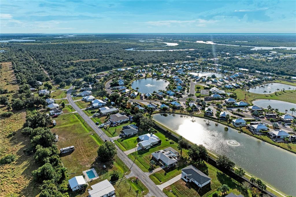 An aerial view shows a residential community with houses, ponds, and surrounding natural landscape — 8867 SW SAND CRANE CIRCLE LOT 21, ARCADIA, FL