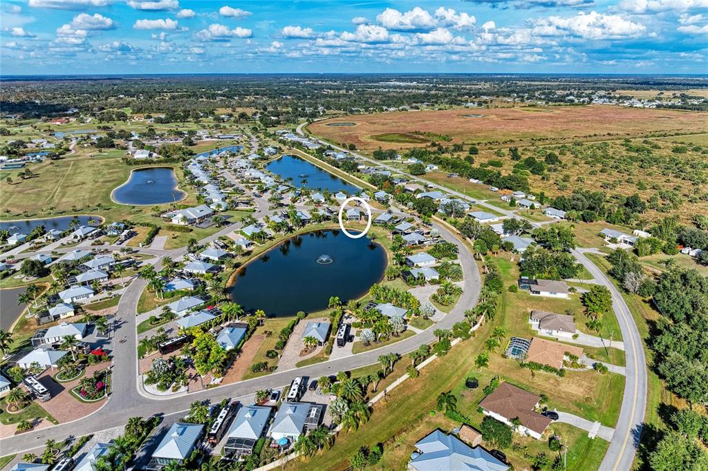 An aerial view shows a residential community with houses surrounding a central pond — 8867 SW SAND CRANE CIRCLE LOT 21, ARCADIA, FL