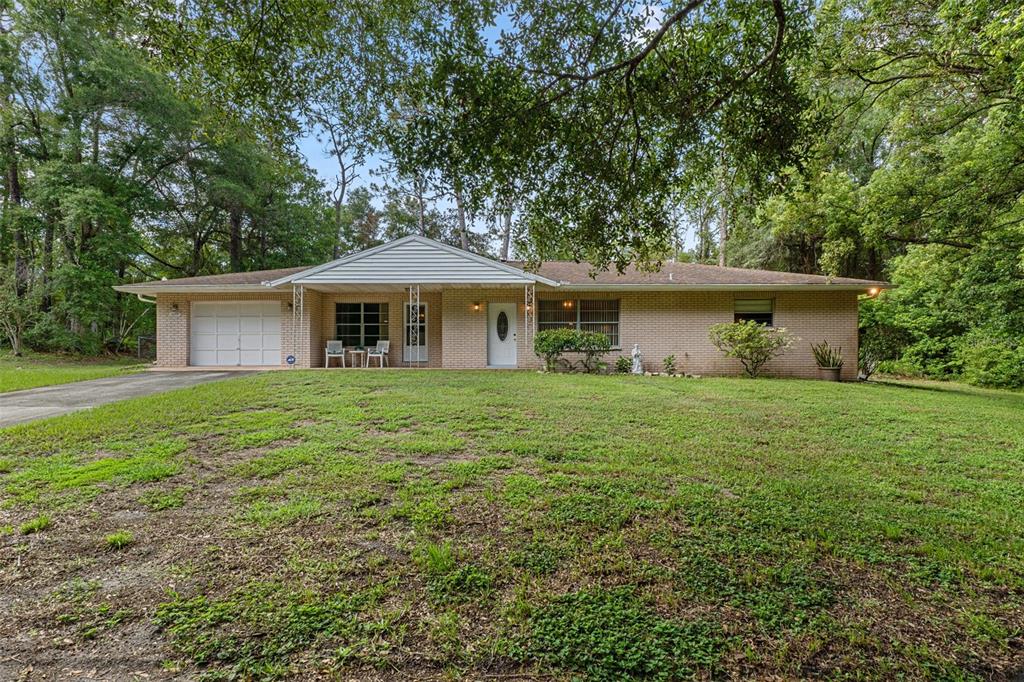 A single-story brick house with a white garage door and a front porch — 6095 ZIRKELS CIRCLE, BROOKSVILLE, FL