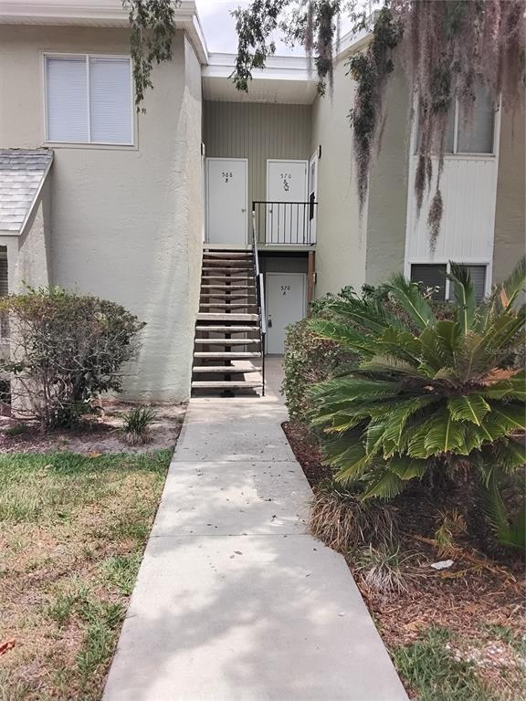 A concrete walkway leads to an exterior staircase and two levels of apartment unit doors — 570 BAHIA CIRCLE UNIT B, OCALA, FL