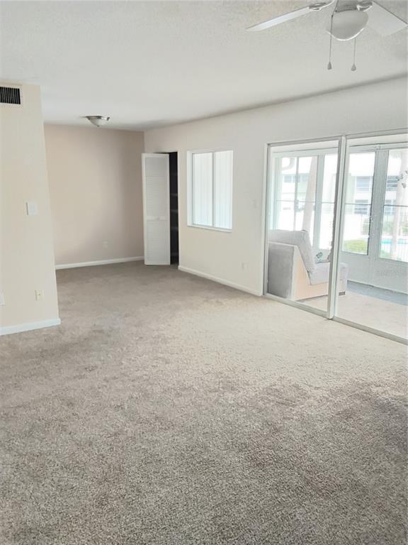A carpeted living room features a ceiling fan, a closet, and sliding glass doors — 570 BAHIA CIRCLE UNIT B, OCALA, FL