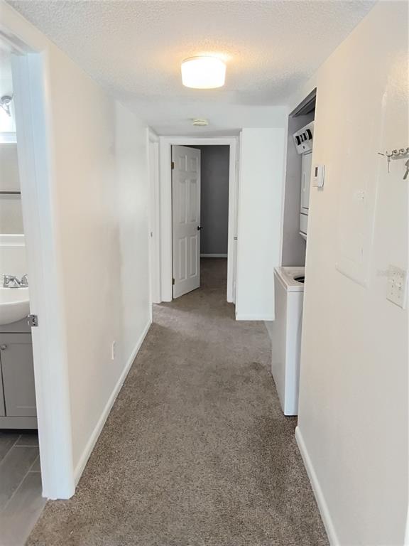 A hallway with carpeted flooring leads to a doorway, featuring a laundry closet and bathroom — 570 BAHIA CIRCLE UNIT B, OCALA, FL