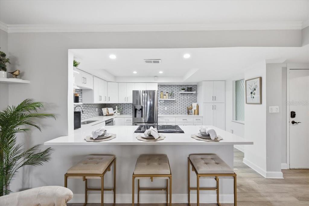 A kitchen with white cabinets, a central island with bar seating, and a tiled backsplash — 4908 38TH WAY S UNIT 401, ST PETERSBURG, FL