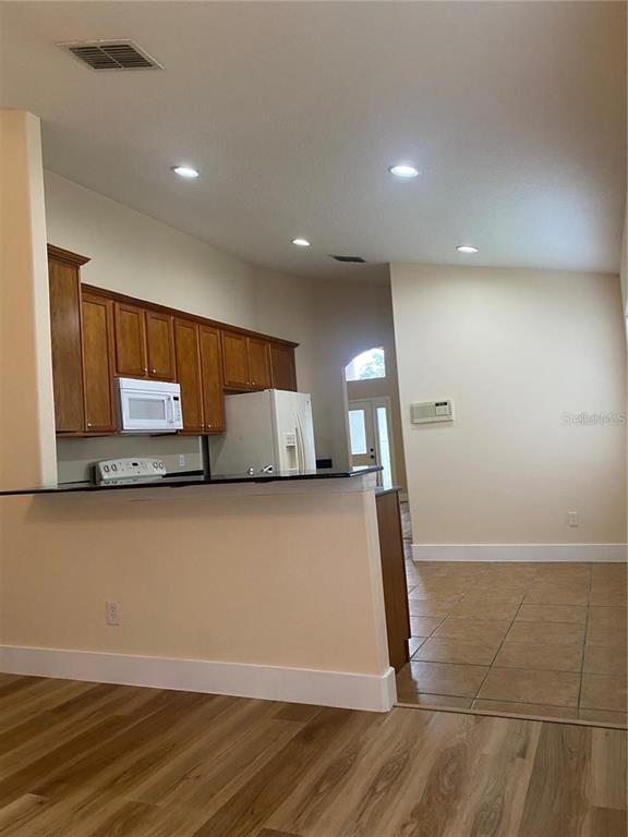 A kitchen with wood cabinets and a breakfast bar overlooks a tiled dining area — 10007 DORIATH CIRCLE, ORLANDO, FL
