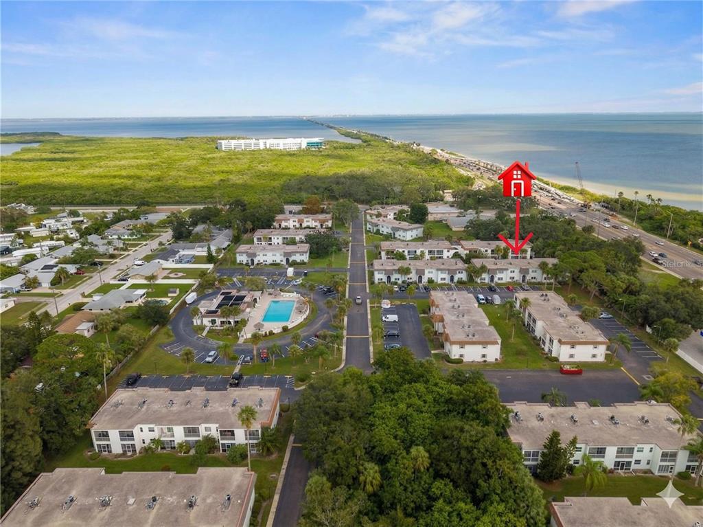 An aerial view shows a multi-building apartment complex with a pool near the coast — 375 S MCMULLEN BOOTH ROAD UNIT 95, CLEARWATER, FL