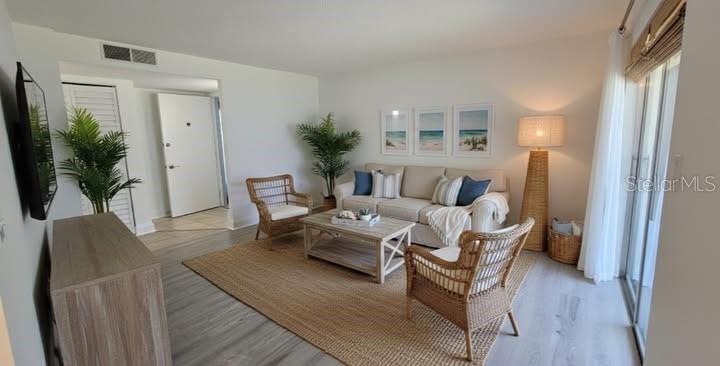 A living room features a beige sofa, wicker chairs, a coffee table, and wood flooring — 375 S MCMULLEN BOOTH ROAD UNIT 95, CLEARWATER, FL