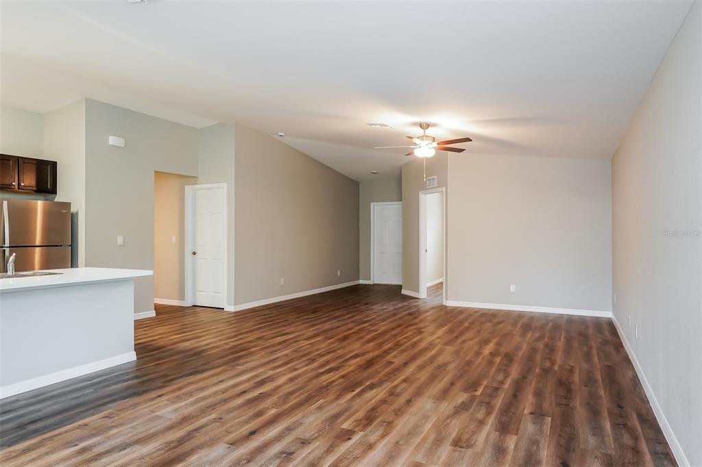 An open-concept living area features wood-look flooring, a ceiling fan, and an adjacent kitchen — 4638 JASLO AVENUE, NORTH PORT, FL