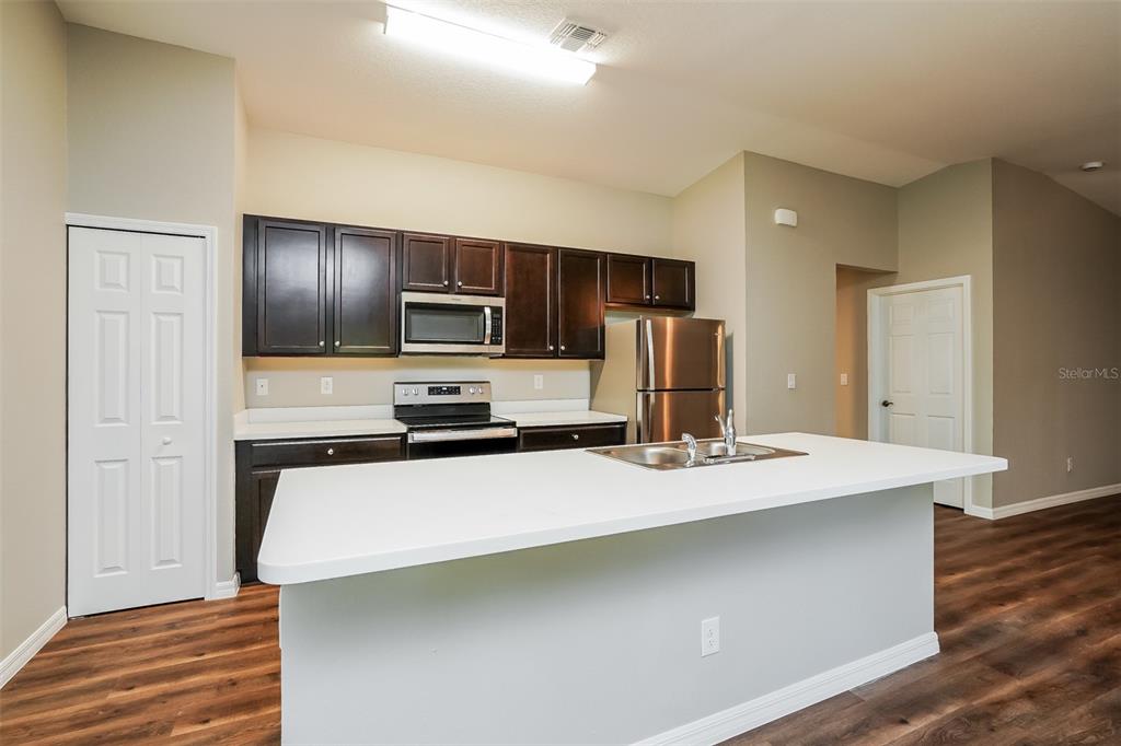 A kitchen features dark wood cabinets, stainless steel appliances, and a white island countertop — 4638 JASLO AVENUE, NORTH PORT, FL