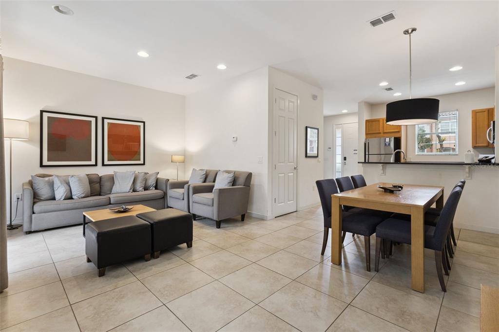 An open-concept living and dining area with tile floors, gray furniture, and a kitchen island — 2711 COUPE STREET, KISSIMMEE, FL