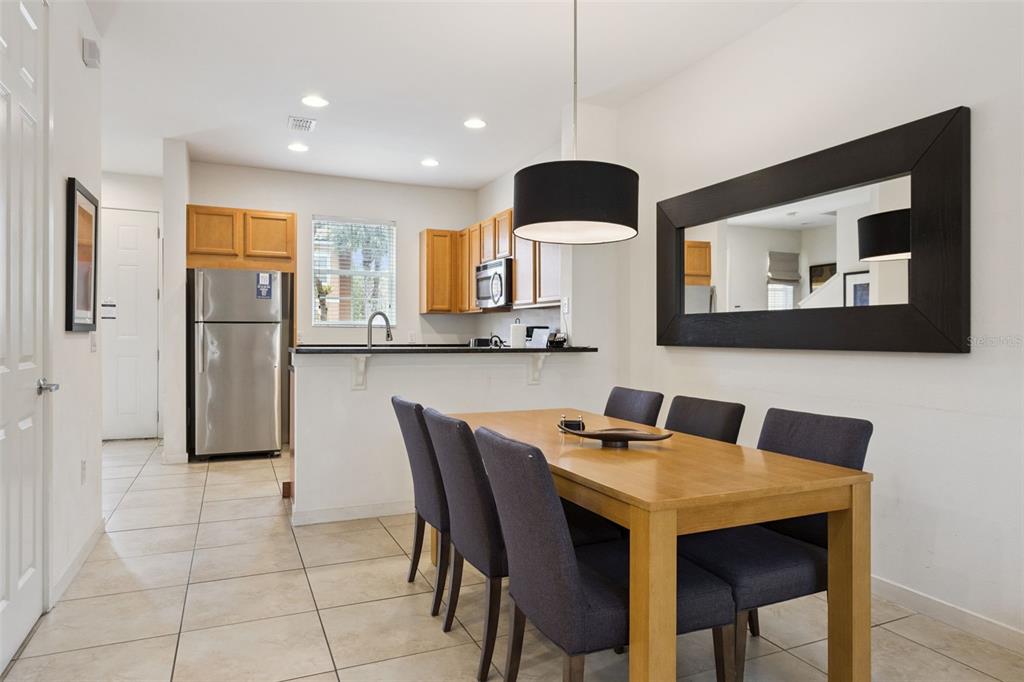 A dining area with a wooden table and chairs sits adjacent to an open kitchen — 2711 COUPE STREET, KISSIMMEE, FL