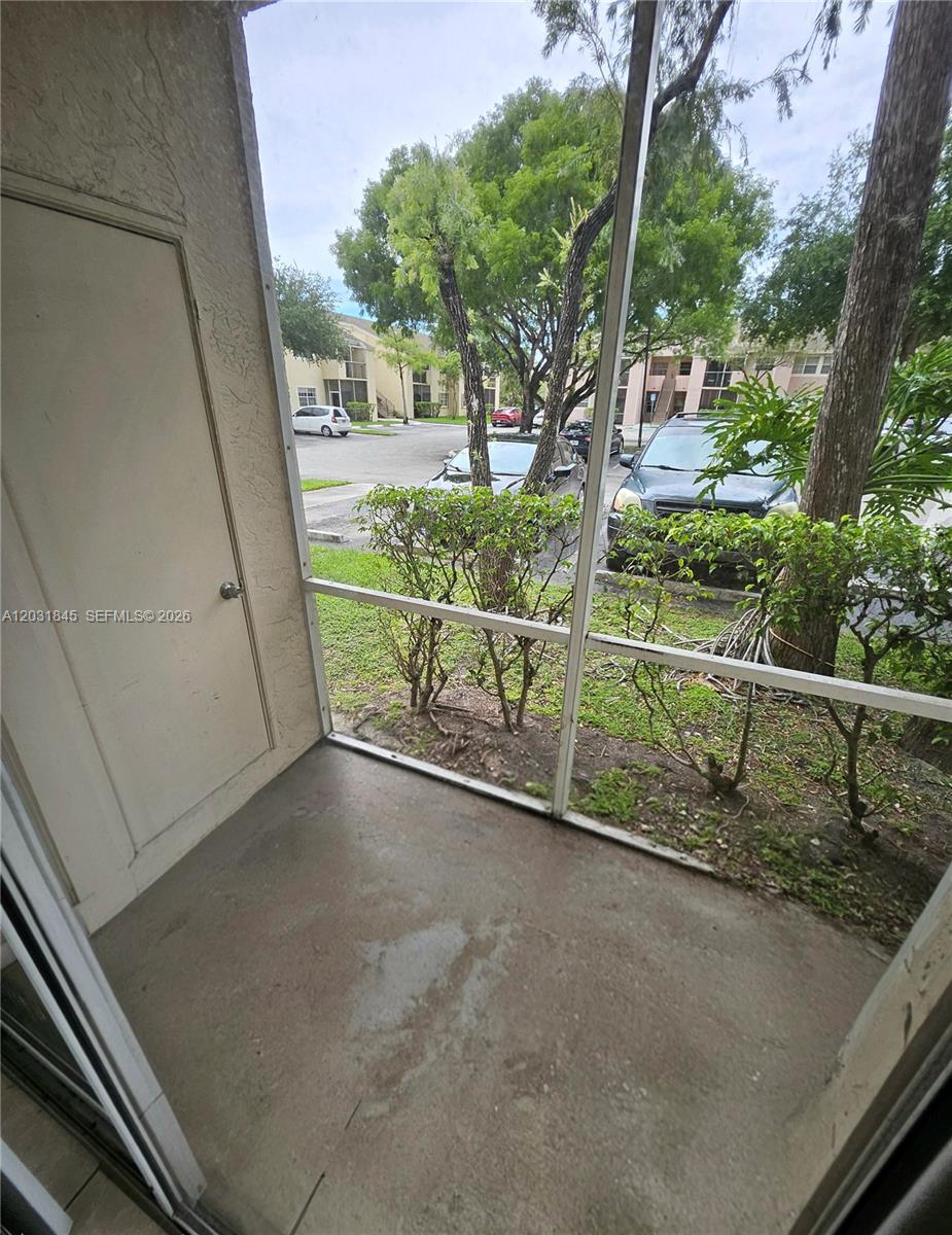 A screened-in patio overlooks a parking lot with several parked cars and trees — 631 Cypress Lake Blvd # E17, Deerfield Beach FL 33064, DEERFIELD BEACH, FL
