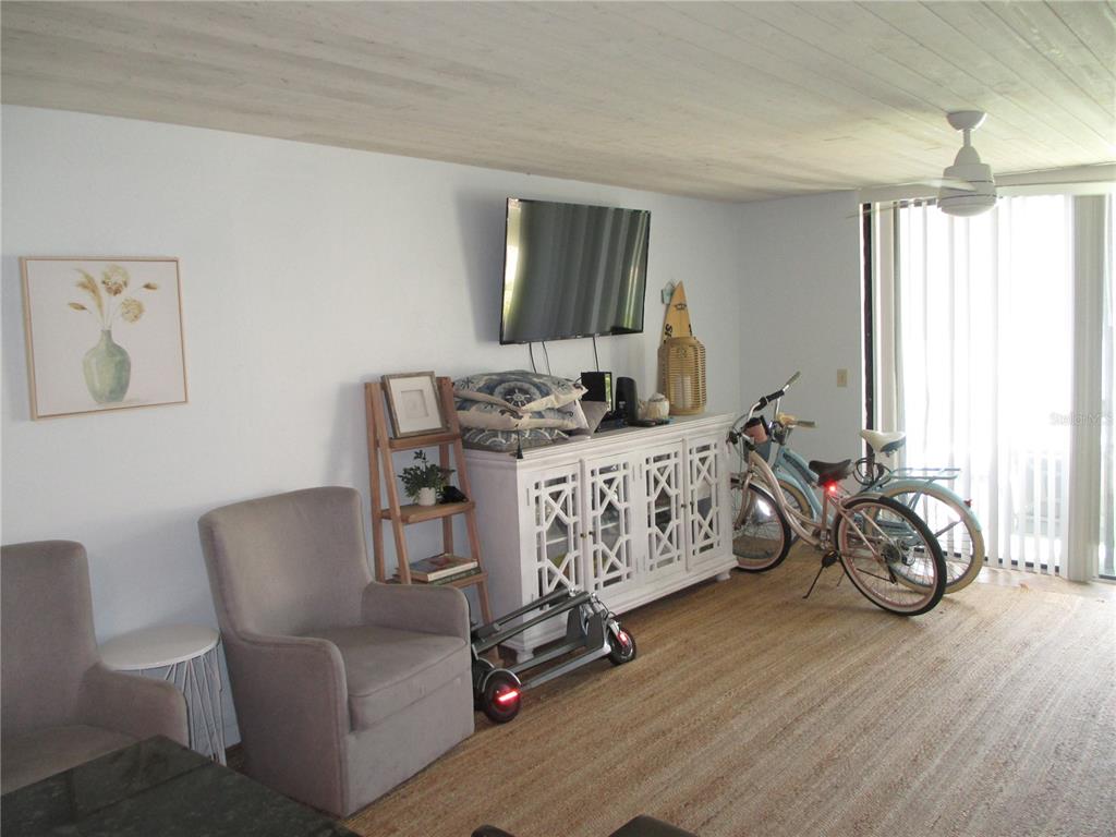 A living room features a white cabinet, two bicycles, a scooter, and two armchairs — 1441 N ATLANTIC AVENUE UNIT 113, DAYTONA BEACH, FL