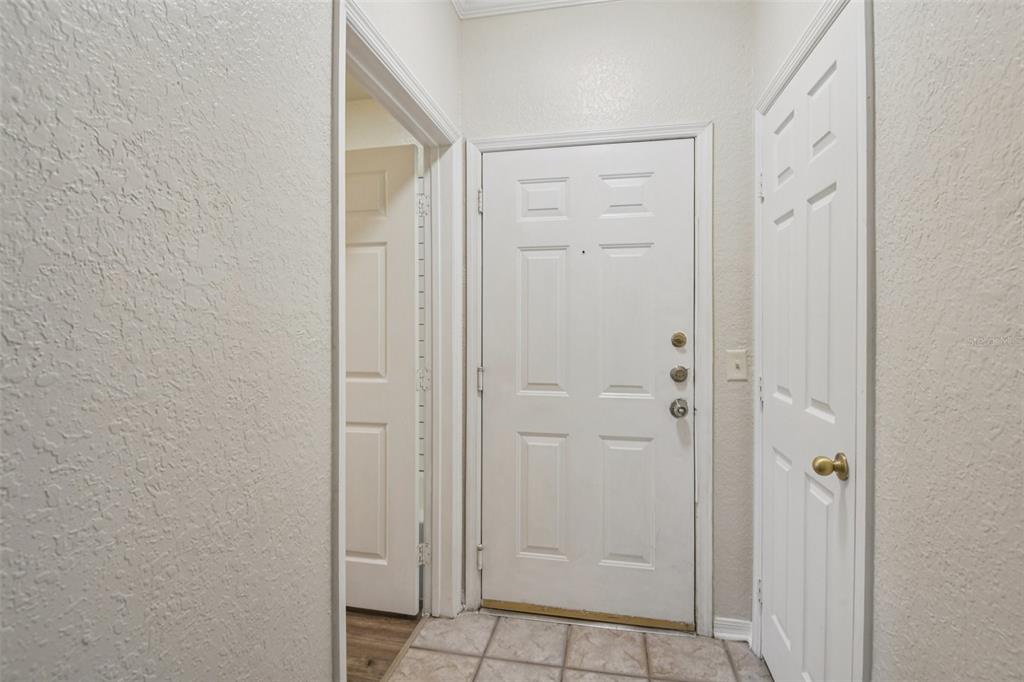 An entryway features a white front door, a tiled floor, and a closed closet door — 18001 RICHMOND PLACE DRIVE UNIT 1213, TAMPA, FL